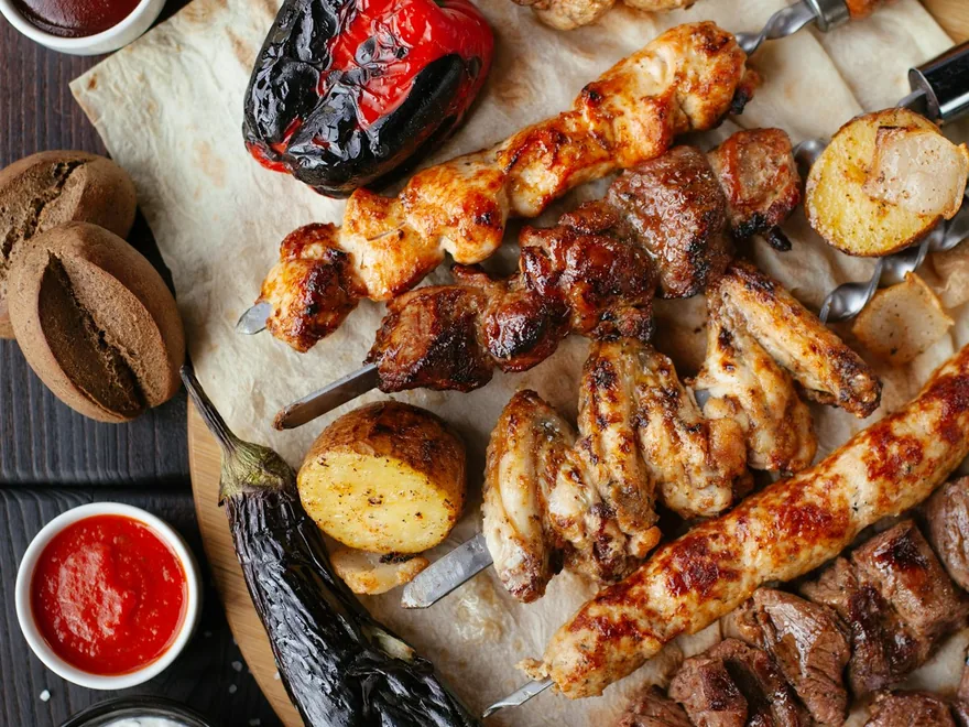 An overhead spread of grilled meats, sides and sauces.