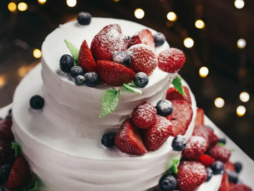 A tiered celebration cake decorated with fresh berries.
