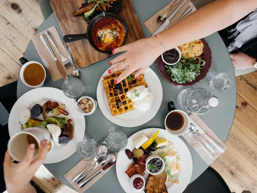 An overhead view of a shared table of dishes, dips and small plates.