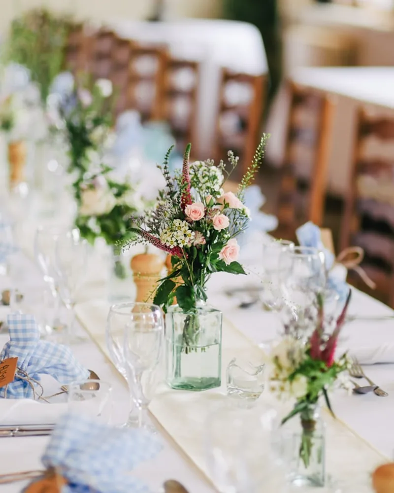 A wedding reception table laid with glassware, candles and flowers.