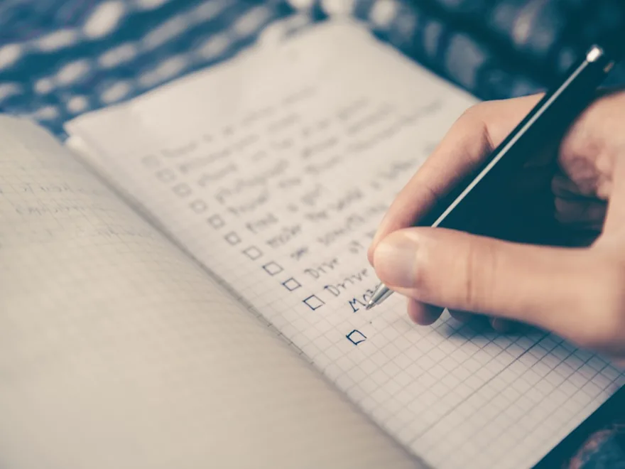 A handwritten planning list and pen on a notebook.