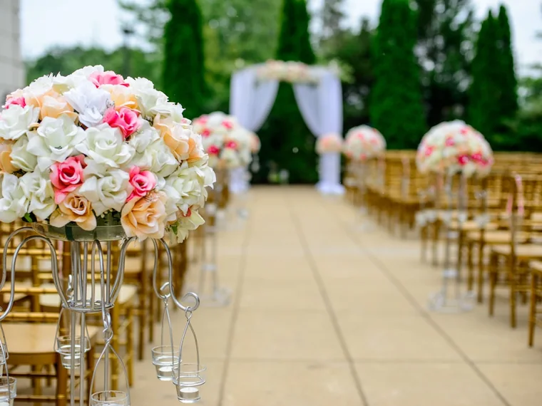 A wedding ceremony aisle lined with floral arrangements and chairs.