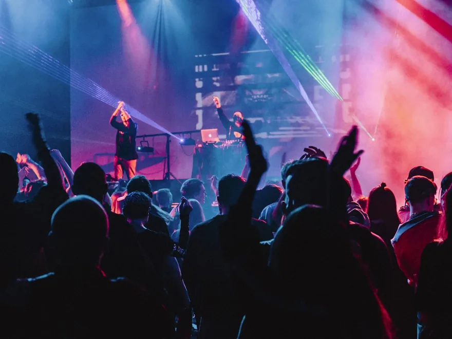 Guests dancing under coloured lighting at an evening event.